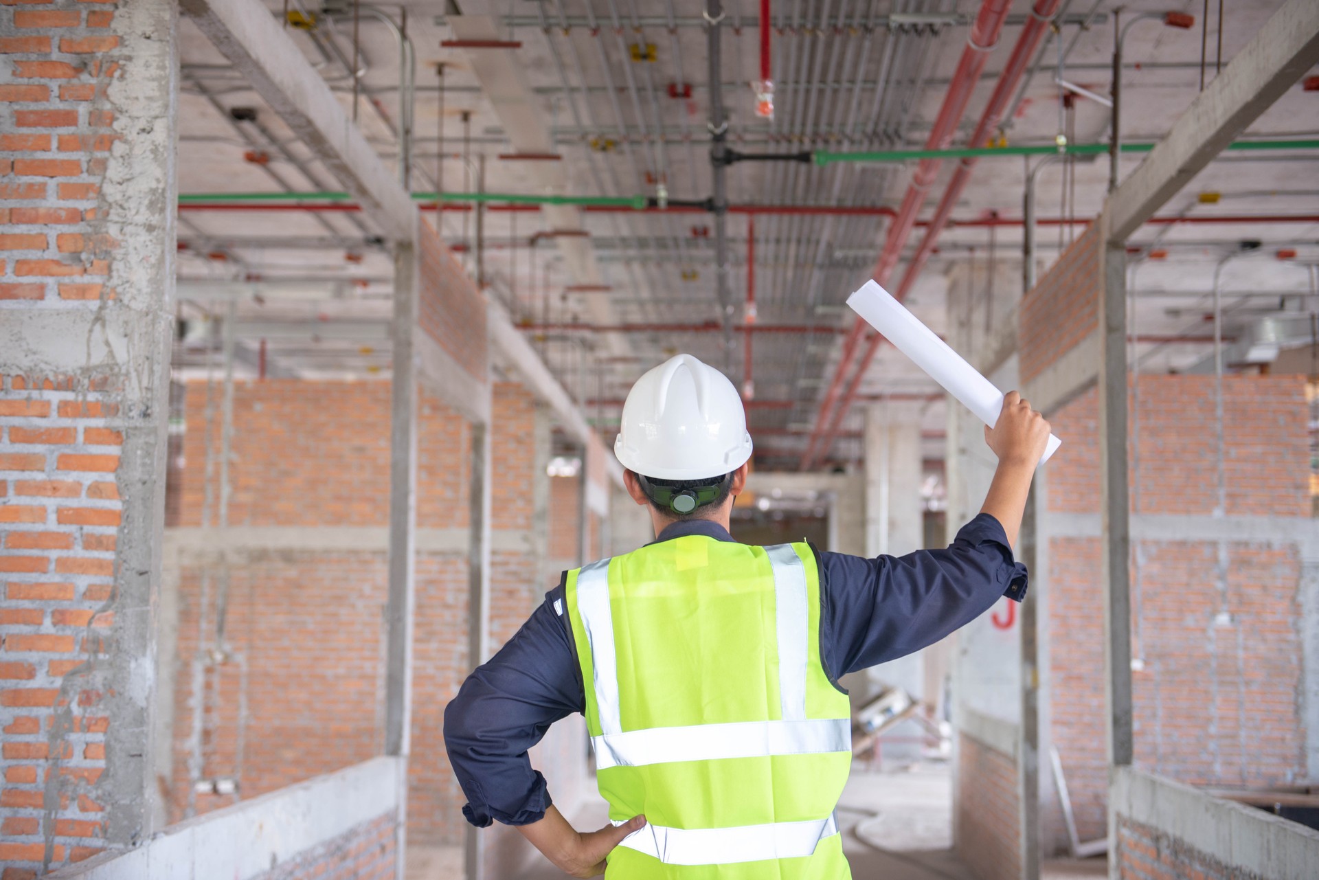 Engineering Consulting People on construction site holding blueprint in his hand. Building inspector. Construction site check drawing